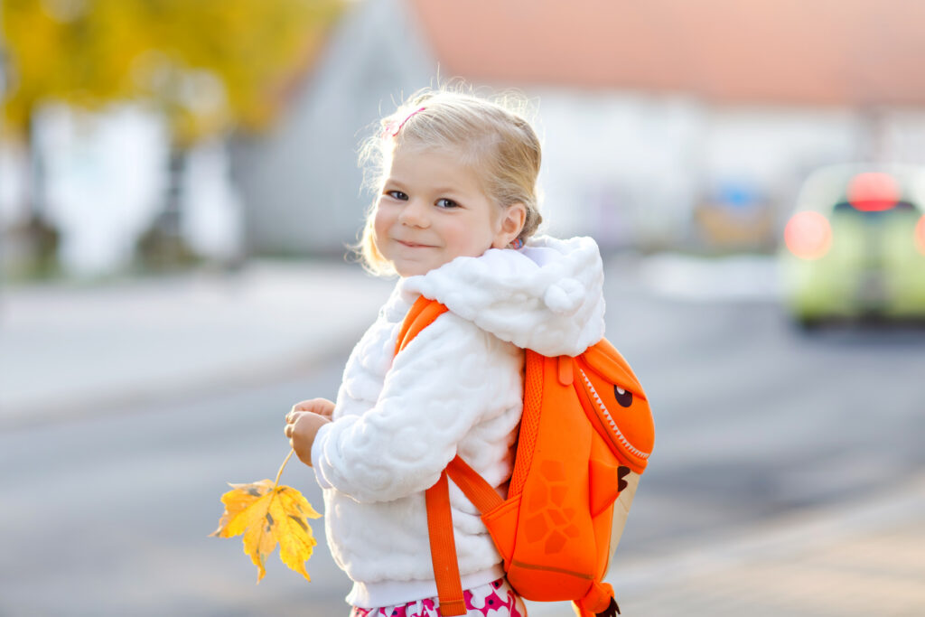 young girl with backpack smiling at the camera